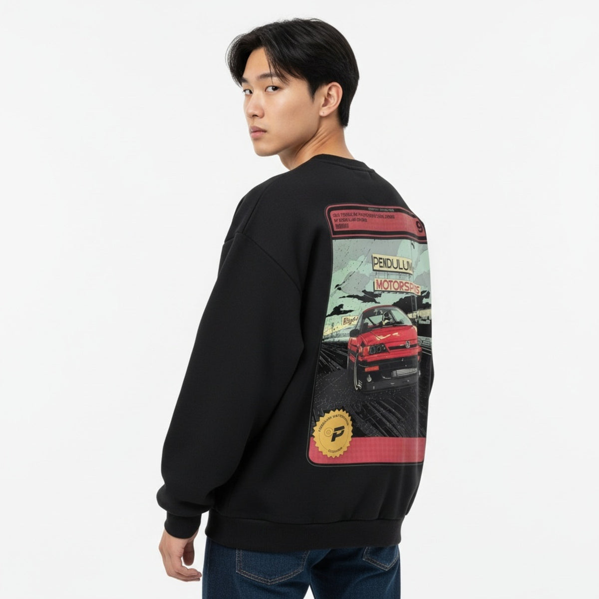 A model wearing the black 1991 Honda CRX Turbo crewneck seen from a back three-quarter angle, with the comic panel of a red boosted CRX across the back